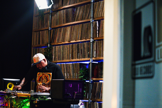 A DJ playing vinyl records at Lulo Records with thousands of albums and music